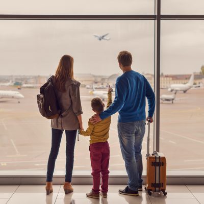 Such large aircraft. Back view shot of young family with luggage standing near window in airport before boarding